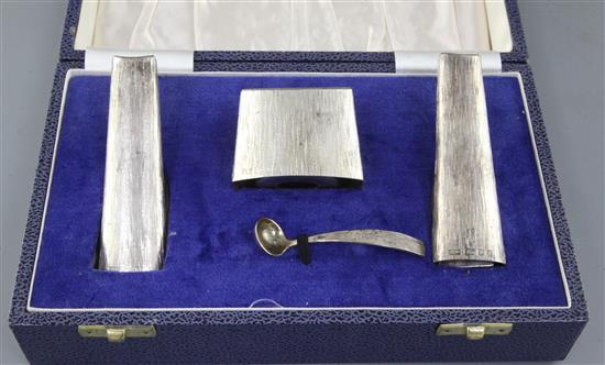 A stylish cased 1970s textured silver three piece condiment set and matching spoon by Mappin & Webb, pepperette 98mm.